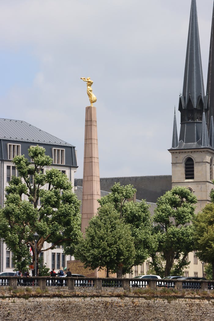 View of the Golden Lady monument with church spires in Luxembourg City.