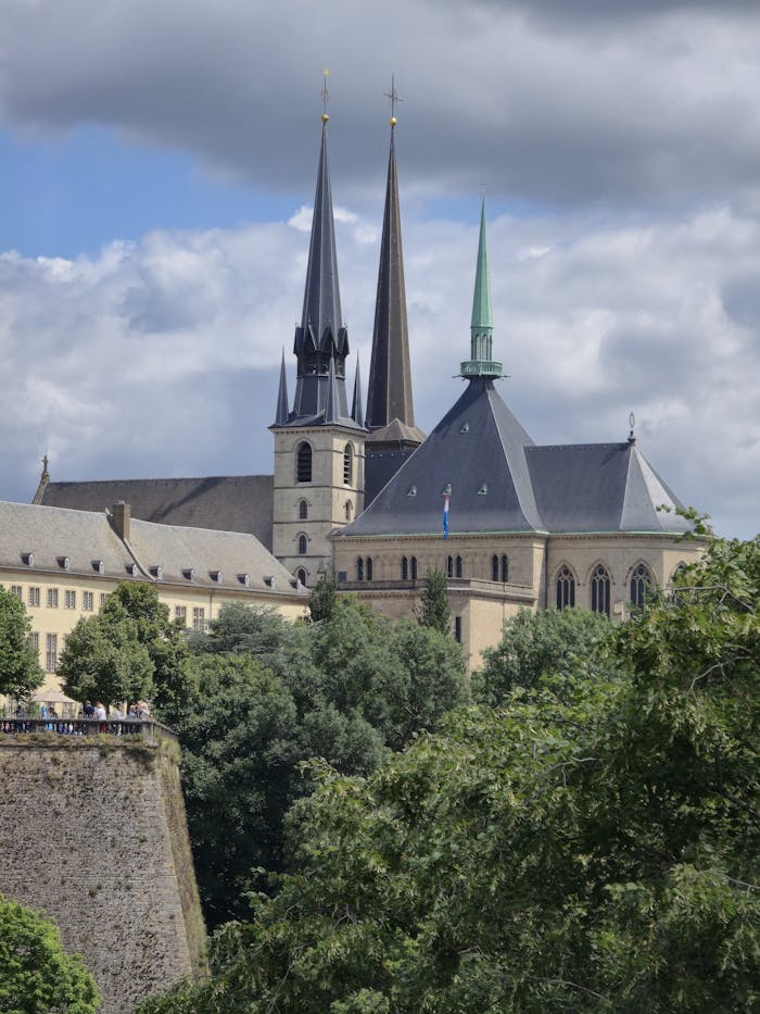A scenic view of Cathedral Notre-Dame and fortress in Luxembourg City under cloudy skies.